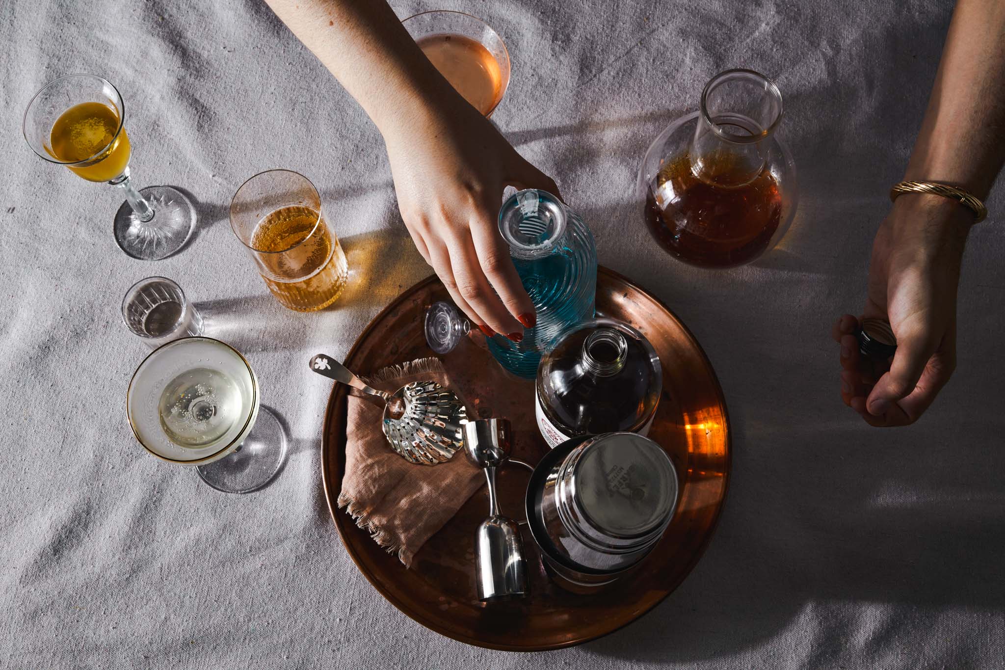 mix of glassware with cocktail tools on a brass tray