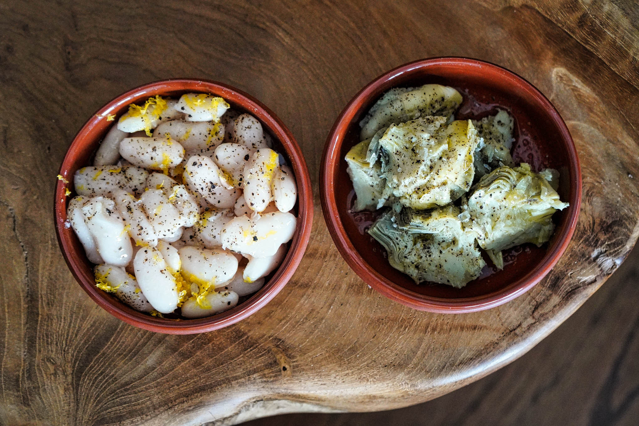 white fava beans with lemon zest in cazuela and artichoke hearts with olive oil in cazuela