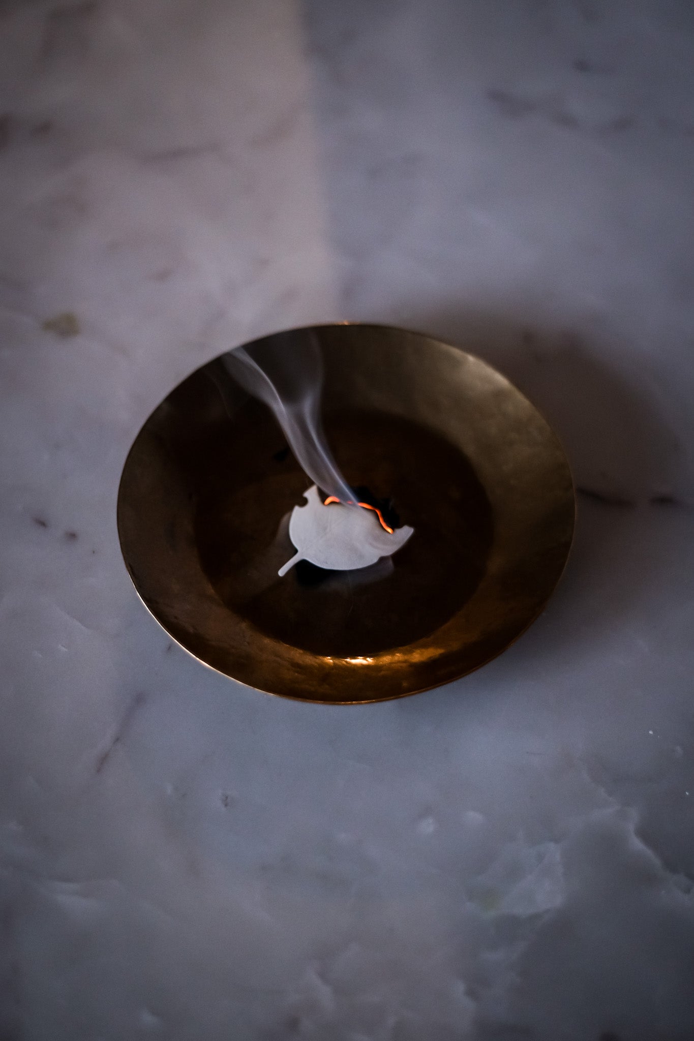 Burning white leaf inside a gold bowl 